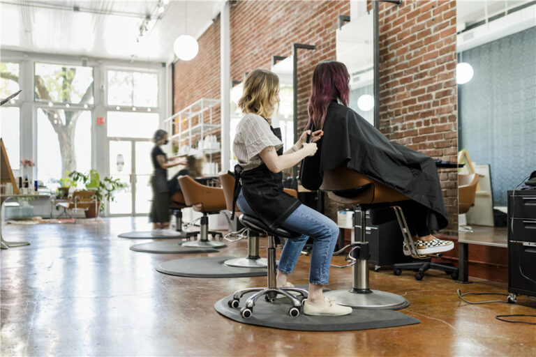 Hairstylist working on a client in a modern salon with exposed brick walls and natural light